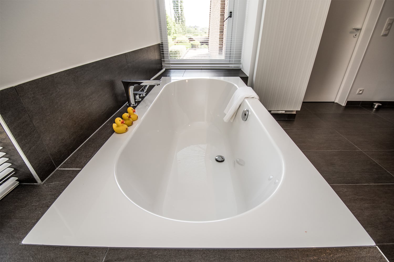 Een ruime bad en grote keramische tegels